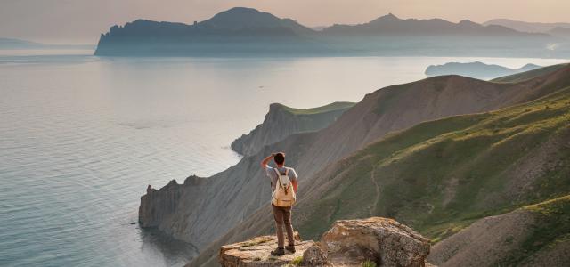 Young Man Travels Alone on the Backdrop of the Mountains