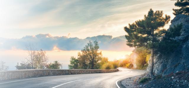 Landscape with rocks, sunny sky with clouds and beautiful asphalt road in the evening in summer